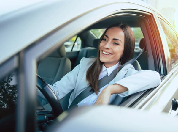 happy woman driving car with the driver's window down