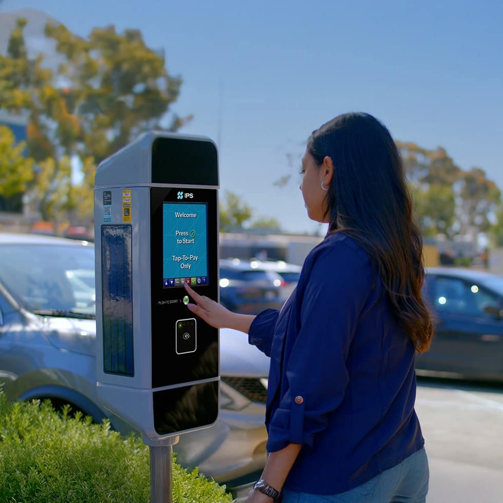 person using an ips group msx multi-space pay station in a parking lot